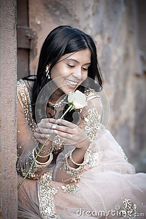 Young beautiful Indian Woman sitting against stone wall outdoors
