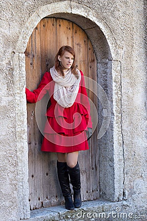 Young beautiful redhaired woman posing in front of the old door