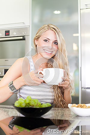 Young beautiful woman enjoying healthy breakfast in the kitchen