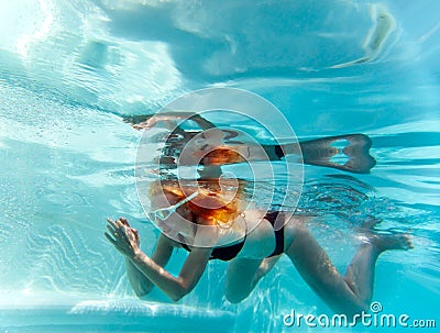 Young beautiful woman with long hair swim in the pool under water.
