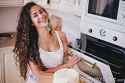 Young beautiful woman making cake at the kitchen