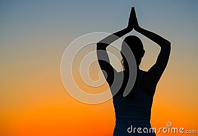 Young Beautiful Woman Practices Yoga on the Sunset