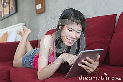 Young beautiful woman using computer tablet on red sofa
