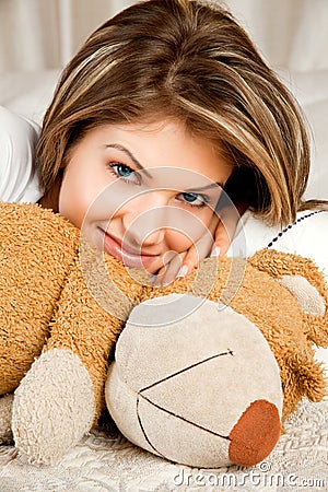 Young beauty woman in the bed with teddy bear