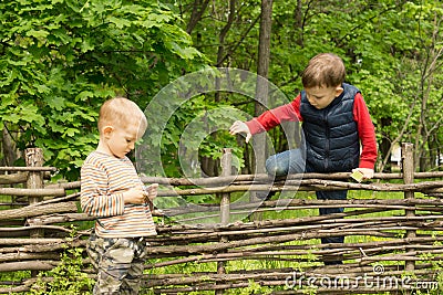 Young boy climbing over a rustic wooden fence