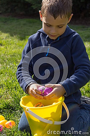 Young Boy Cracks Open an Easter Egg Over a Filled Bucket