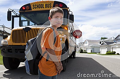 Young boy crossing in front of yellow school bus