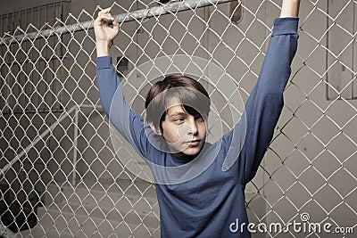 Young boy posing on a chain-link fence