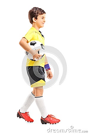 Young boy walking and holding a football