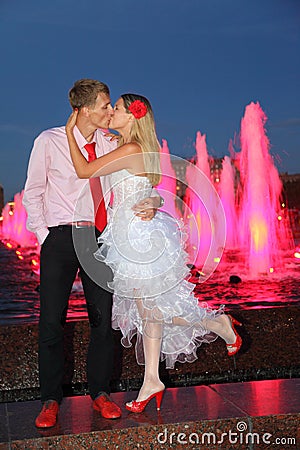 Bride and groom kiss near pink fountains