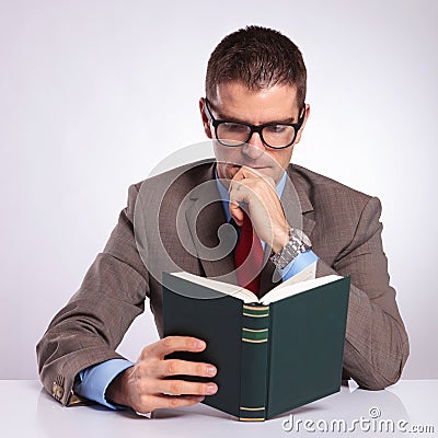 Young business man reading a book at his desk