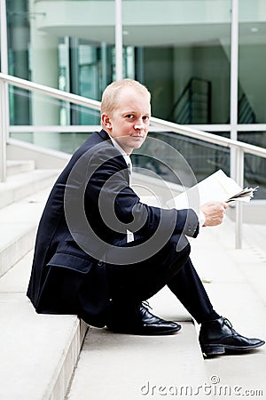 Young business man is reading newspaper outdoor