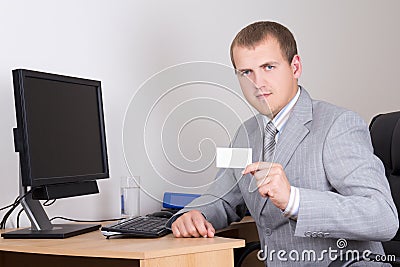 Young business man sitting in office and showing visiting card