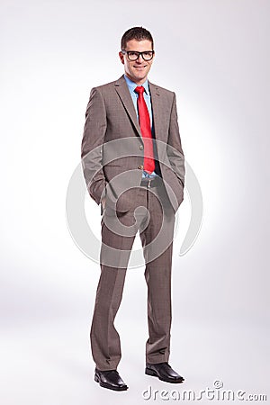 Young business man smiles with both hands in pockets