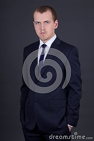 Young business man in suit over grey