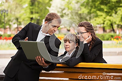Young business man and woman using laptop in park