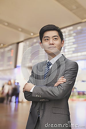 Young businessman with arms crossed at the airport, Beijing, China