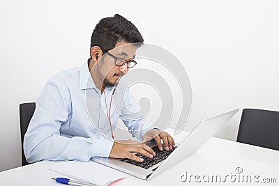 Young businessman listening music while using laptop in office