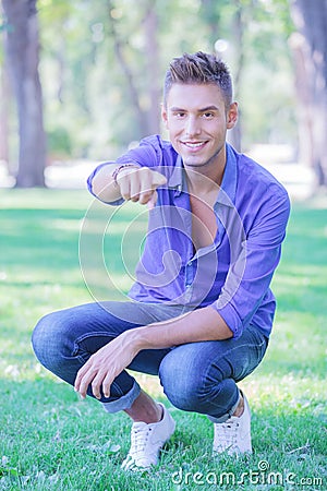 Crouched man pointing at you in park