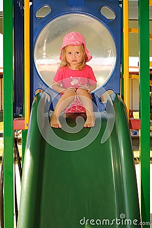 Young child looking sad on a playground slide