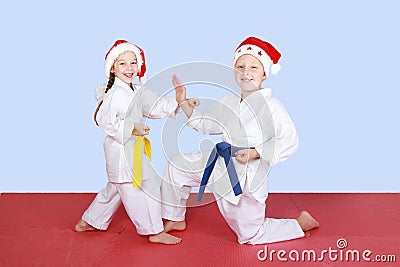 Young children in caps Santa Claus coach exercise karate