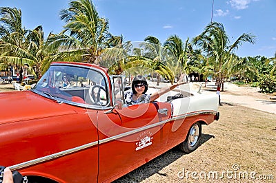 A young Chinese reporter waving out her hand in an old american car