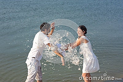 Young couple fighting pillows on the beach