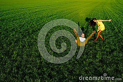 Young couple having fun on the green field in the spring or summ