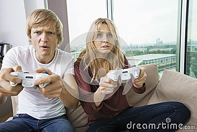 Young couple playing video game in living room at home