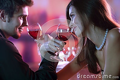 Young couple sharing a glass of red wine in restaurant, celebrat