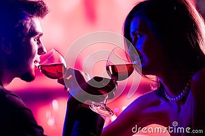 Young couple sharing a glass of red wine in restaurant, celebrat