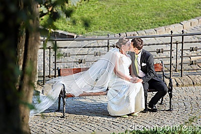 Young couple sitting on a bench and kissing in a hug