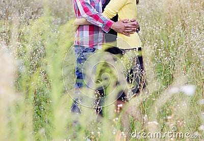 Young couple standing in meadow with arms around each other