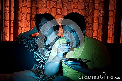 Young couple watching a movie on tv.