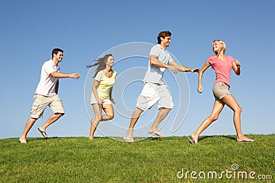 Young couples running through field