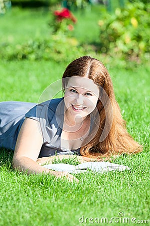 Young cute woman with an open book resting on green