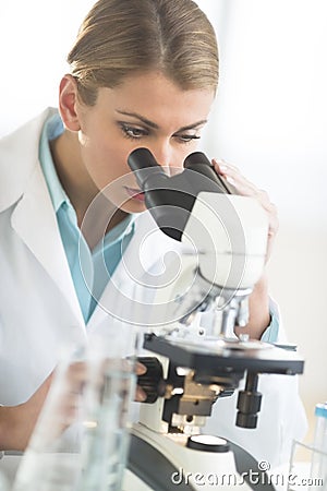 Young Doctor Using Microscope At Desk In Laboratory