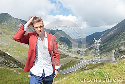 Young fashion man adjusts hair outdoors