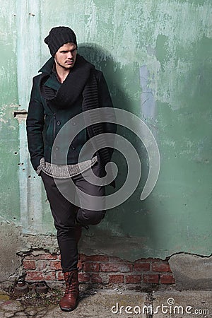 Young fashion man leans on old wall