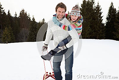 Young Father And Daughter In Snow With Sled