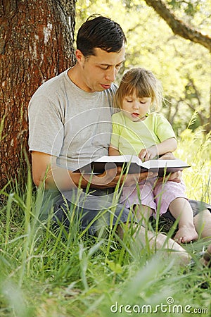 Young father with his little daughter reads the Bible