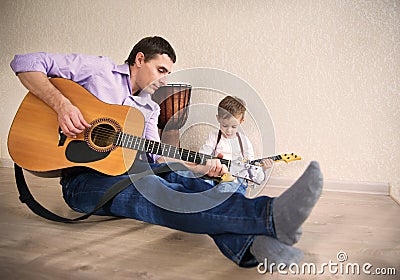 Young father and little son playing guitar