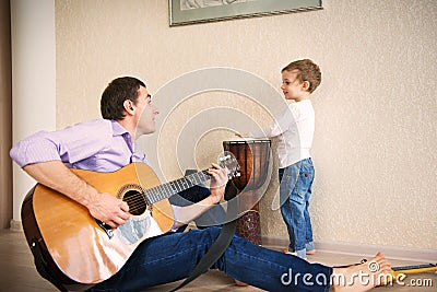 Young father and little son playing guitar