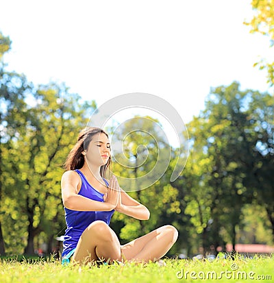 Young female athlete in sportswear doing yoga exercise seated on