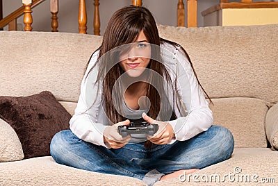 Young female playing video-games concentrating on couch at home