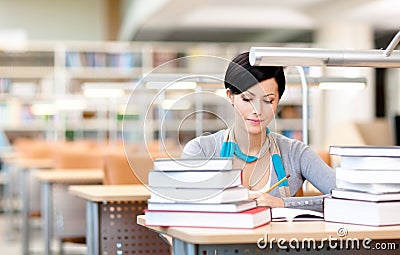 Young female studies with piles of books