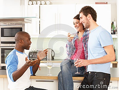 Young Friends Enjoying Glass Of Wine In Kitchen