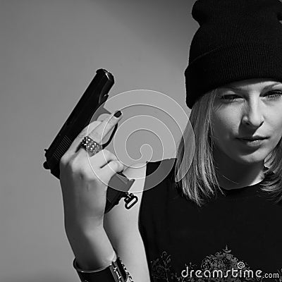 Young girl in a dark cap with a raised gun. Blonde with a gun.