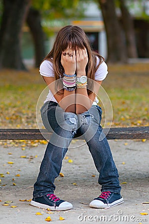 Young girl hides her face with hands