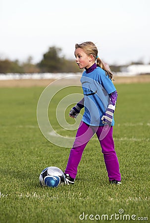 A young girl kicking a soccer ball